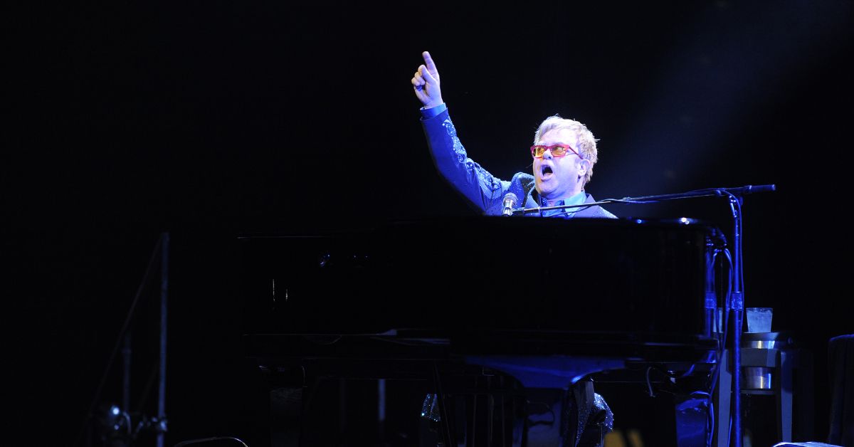 Elton John looking defiant behind a piano