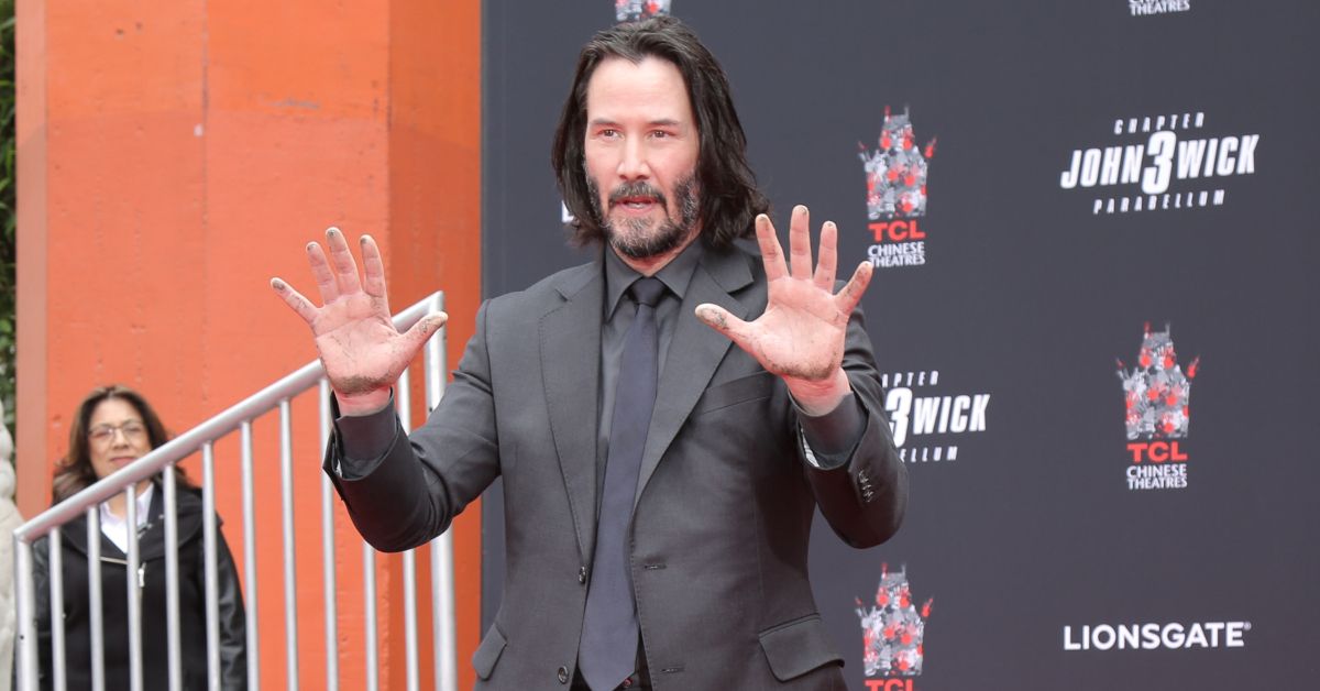 Keanu Reeves holding his hands up like his surrendering