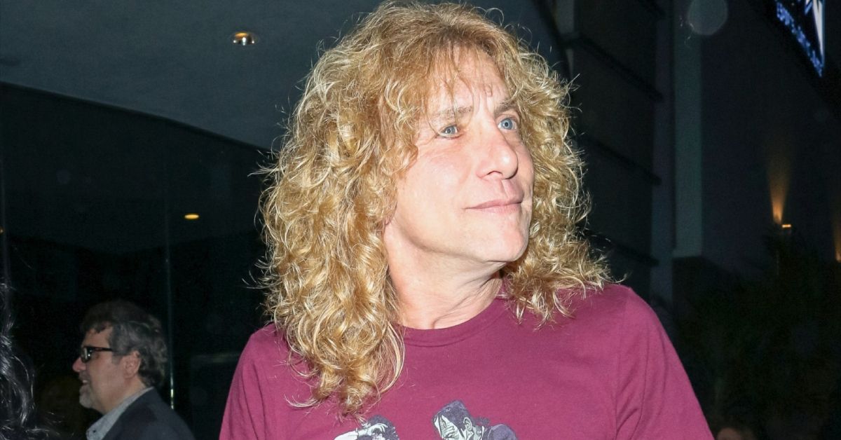 Steven Adler with curly hair wearing a purple t-shirt