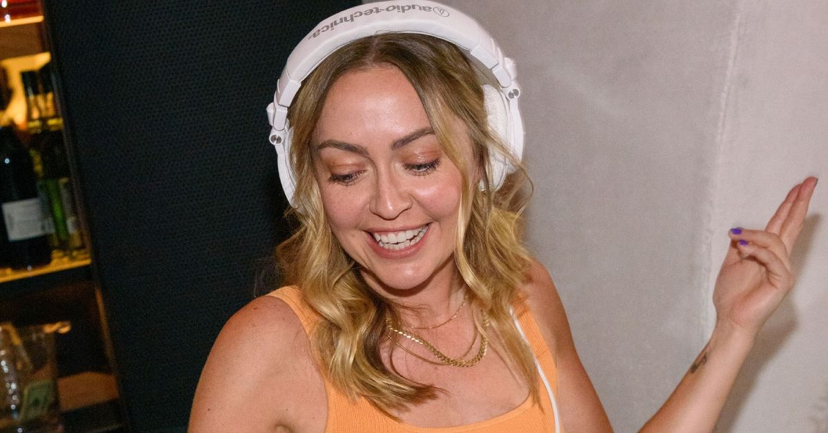 Brandi Cyrus smiling while working as a DJ wearing headphones