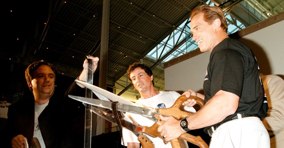 Arnold Schwarzenegger and Sylvester Stallone cutting the ribbon at a Planet Hollywood opening in 1999