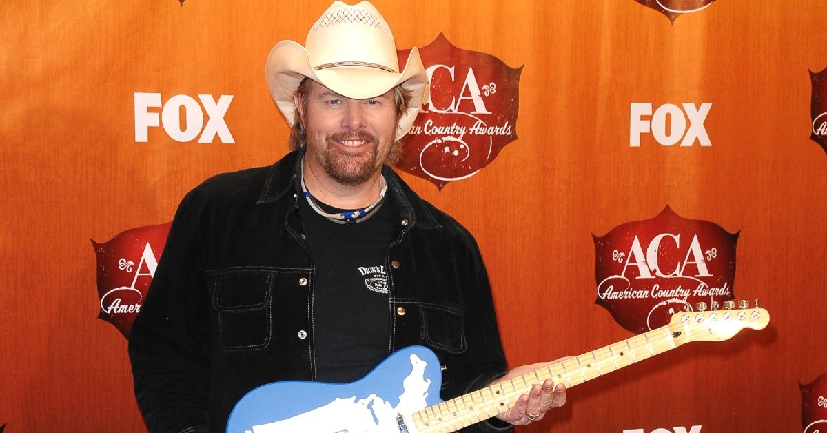 Toby Keith smiling and holding a guitar