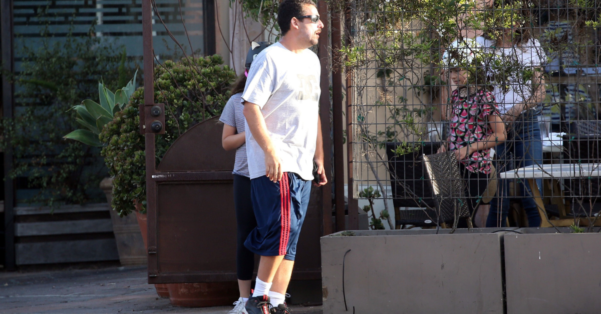 Adam Sandler wearing basketball shorts and sneakers 