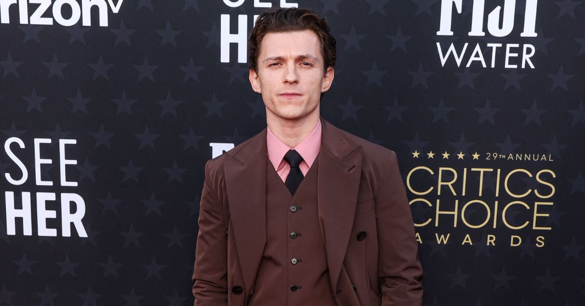 Tom Holland wearing a brown suit and posing at the 2024 Critics Choice Awards