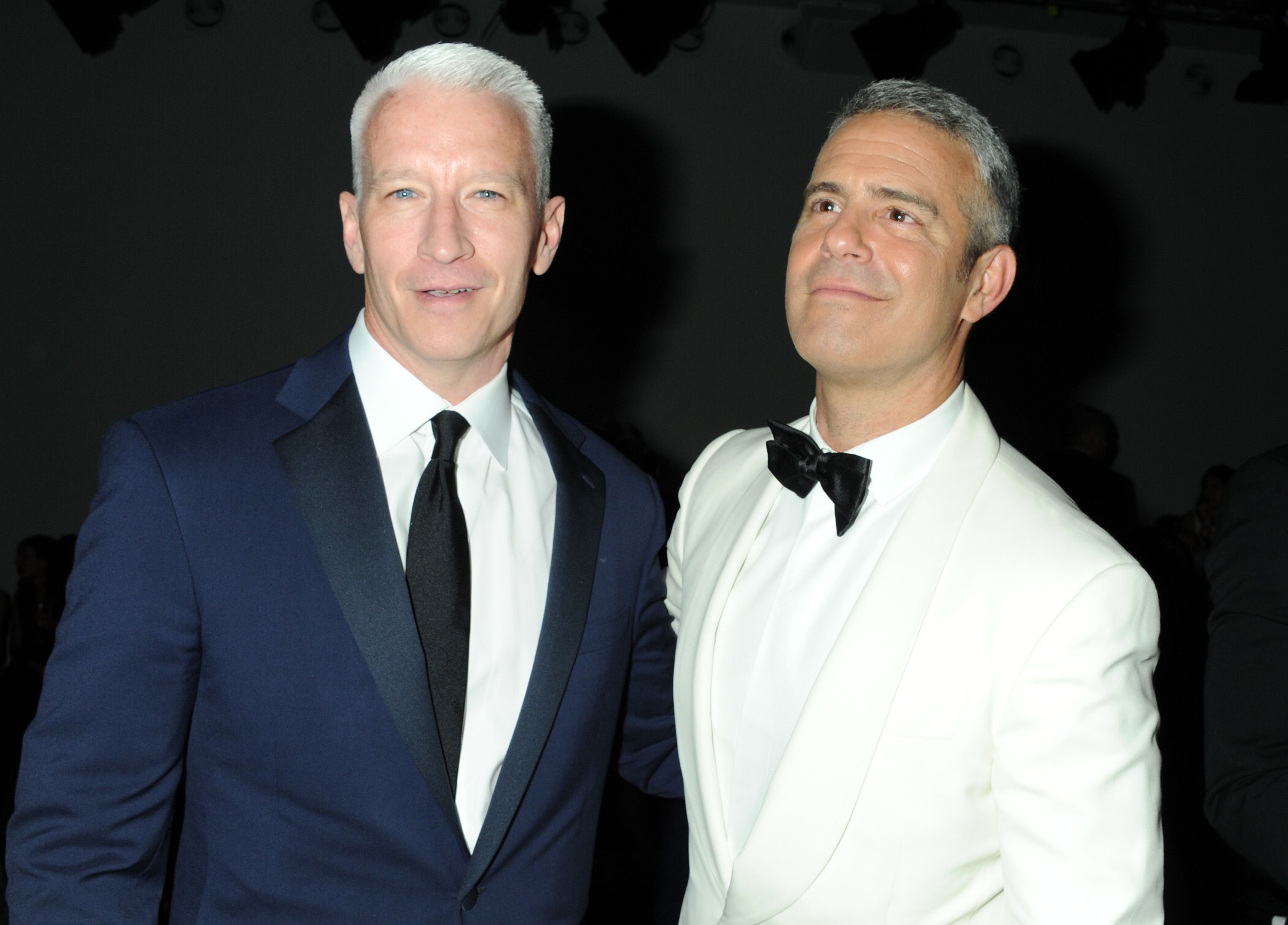 Anderson Cooper and Andy Cohen smile in suits