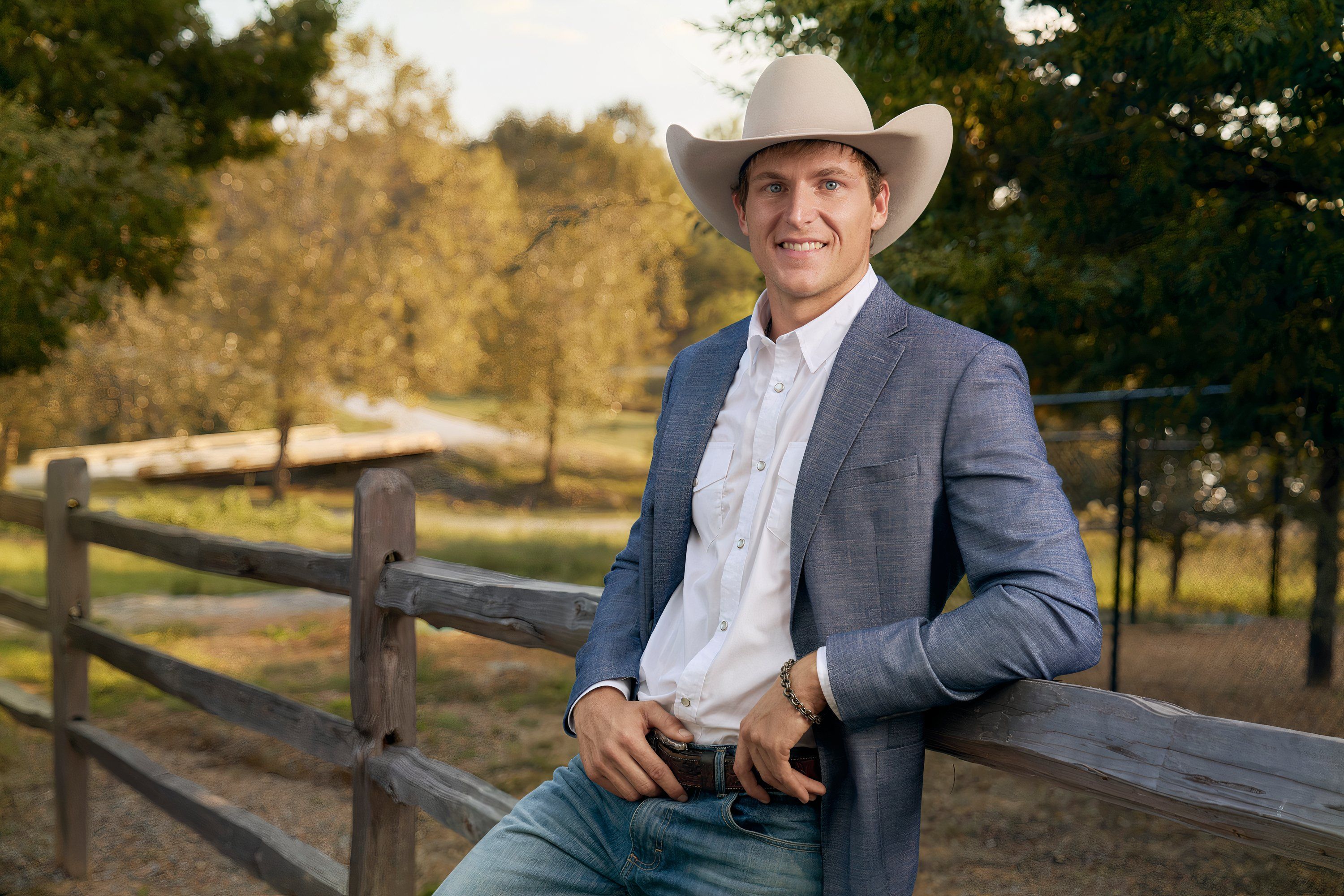 a man poses in a gray suit and white cowboy hat