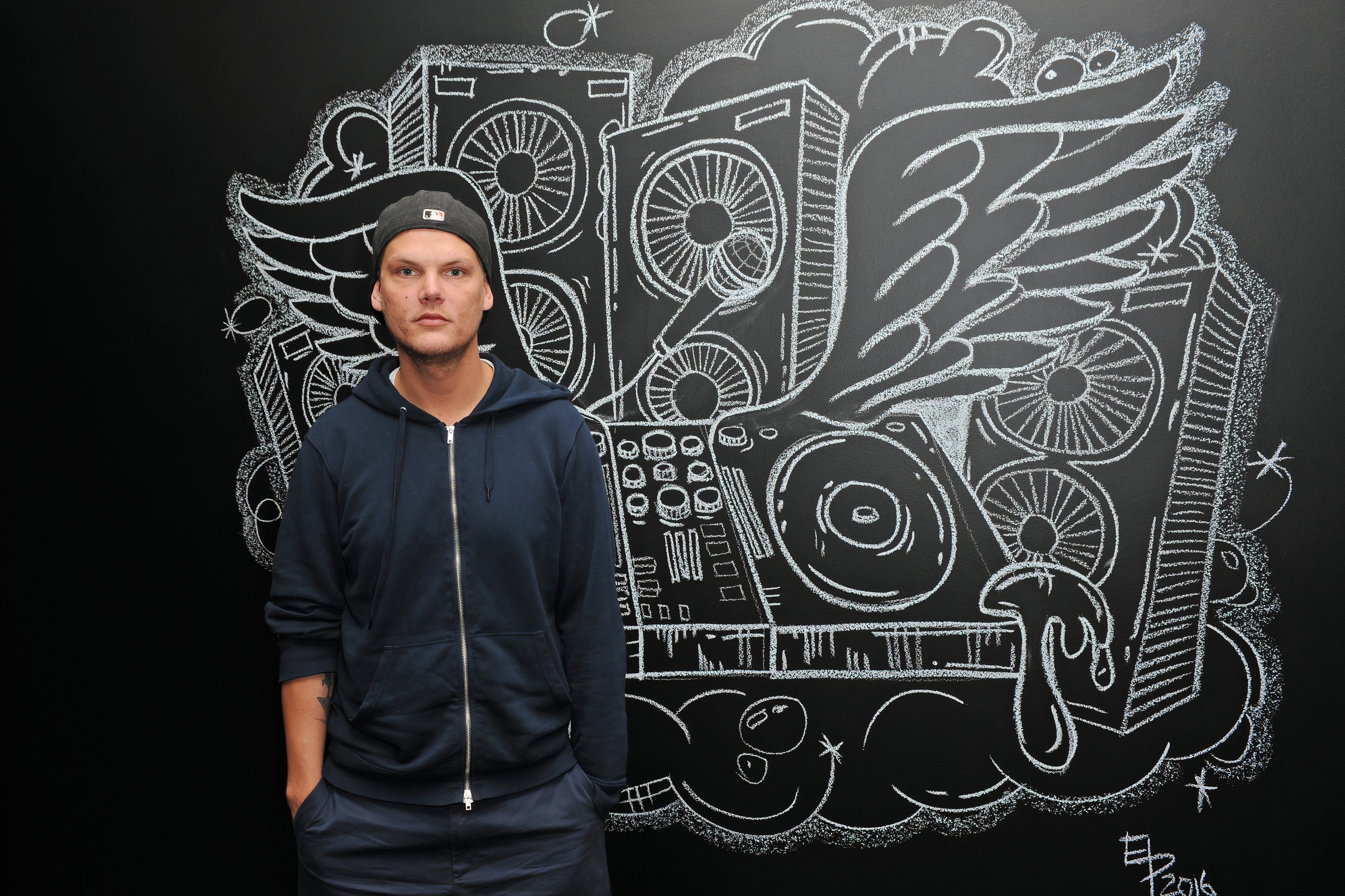 Avicii stands before a black and white mural