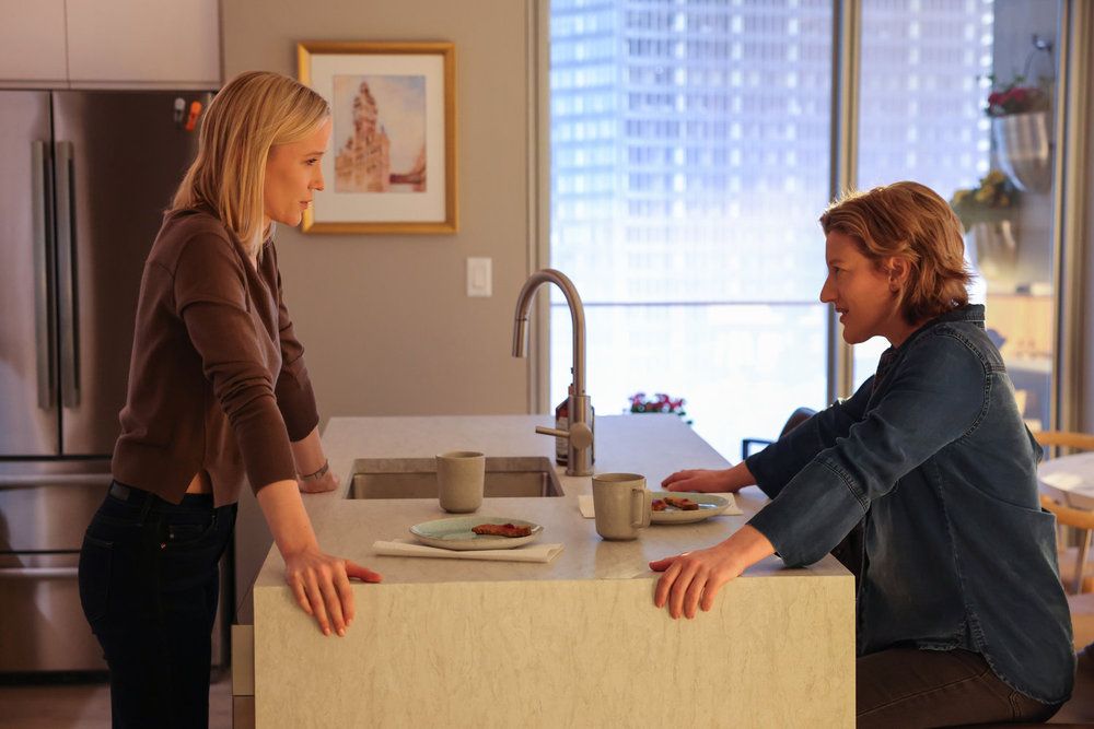 Chicago Med's Jessy Schram as Dr. Hannah Asher and Erin Anderson as Elizabeth Lizzy Asher talking in an apartment