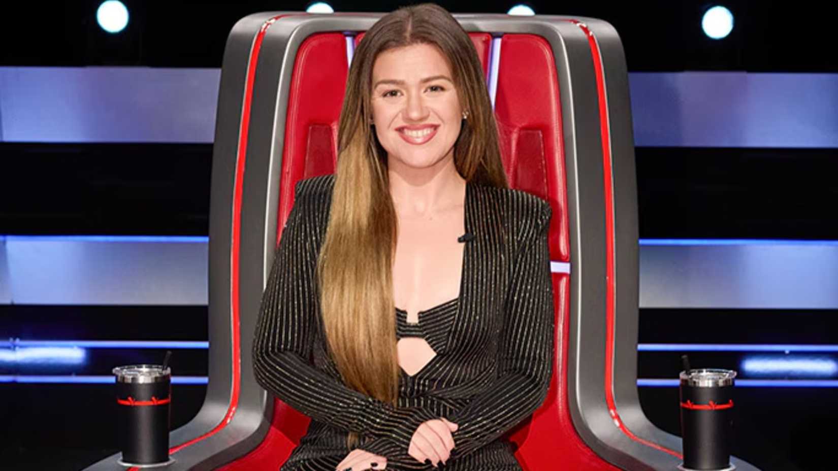 Voice coach Kelly Clarkson smiles in her chair